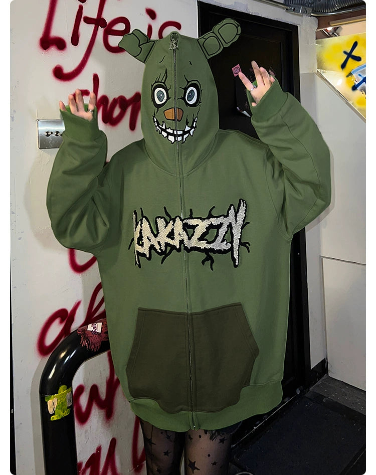 Wearing a Seakoff hoodie inspired by Springtrap, with bear ears and a cartoon face on the hood, hands raised. This oversized green zip-up sweatshirt evokes Five Nights at Freddy&