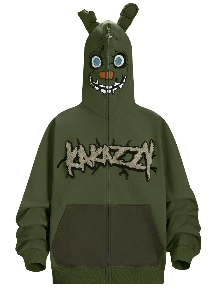 The Seakoff Springtrap-Inspired Hoodie is an oversized green zip-up sweatshirt featuring a cartoon monster face with big eyes and sharp teeth. Perfect for horror game fans, it has "KARAZZI" embroidered in jagged font, evoking Five Nights at Freddy&