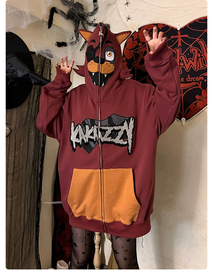 A person in a Seakoff Foxy-Inspired Hoodie, an oversized red zip-up design perfect for Five Nights at Freddy’s fans, poses with raised hands against a Halloween-themed backdrop.