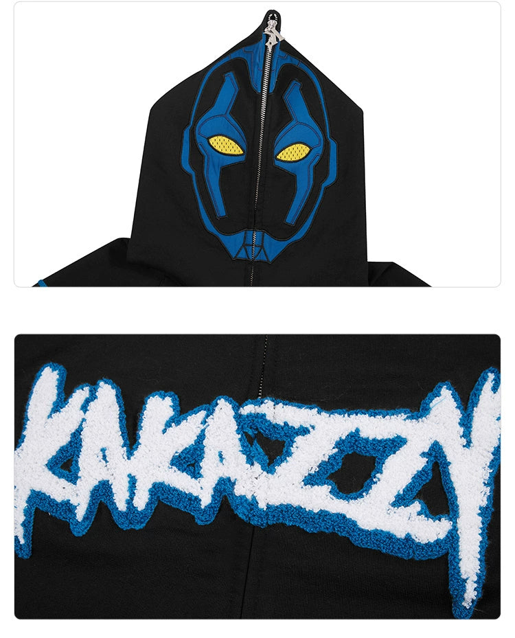 Close-up of a Seakoff Cyberpunk Superhero-Inspired Hoodie, 400GSM oversized and black with a graphic hood resembling a mask with yellow eyes and blue details. Perfect for sci-fi fans, it features bold "KAKAZZY" lettering on the chest in white with blue outlines for a futuristic style.
