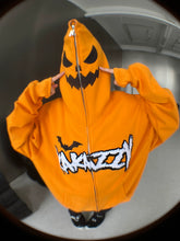 Wearing a Seakoff Halloween Pumpkin Hoodie – an oversized 400GSM orange zip-up sweatshirt with a jack-o’-lantern hood and "AKAZY" on front, someone pulls it snugly over their head. The plain room&