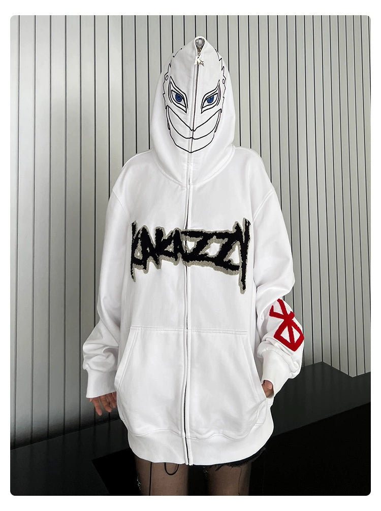 A person is wearing the Berserk Griffith-Inspired Hoodie, a 400GSM oversized white zip-up sweatshirt featuring a hood displaying a printed face with blue eyes. "KAZZY" decorates the chest, and fans will spot a red symbol on the sleeve against vertical stripes in the background.