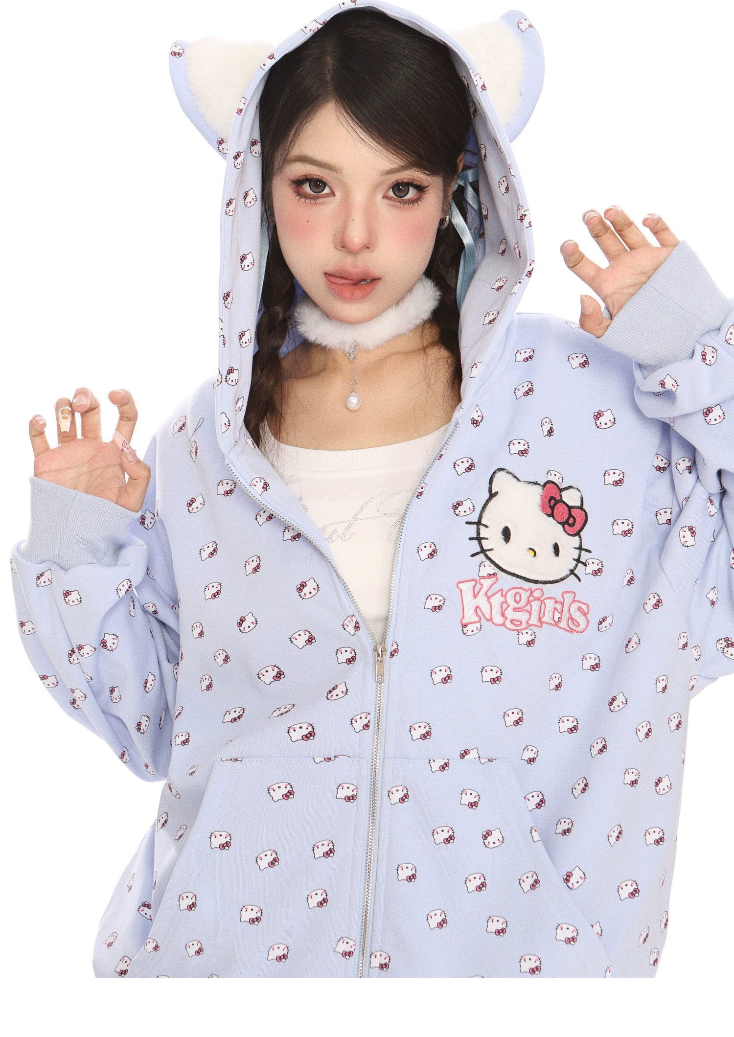 Someone is wearing a Seakoff Hello Kitty Pink Kawaii Hoodie, an oversized zip-up with cat ear hood and all-over print. The hoodie is partially zipped, revealing a white top underneath as the person poses with hands raised to their face, capturing the essence of Kawaii Fashion.