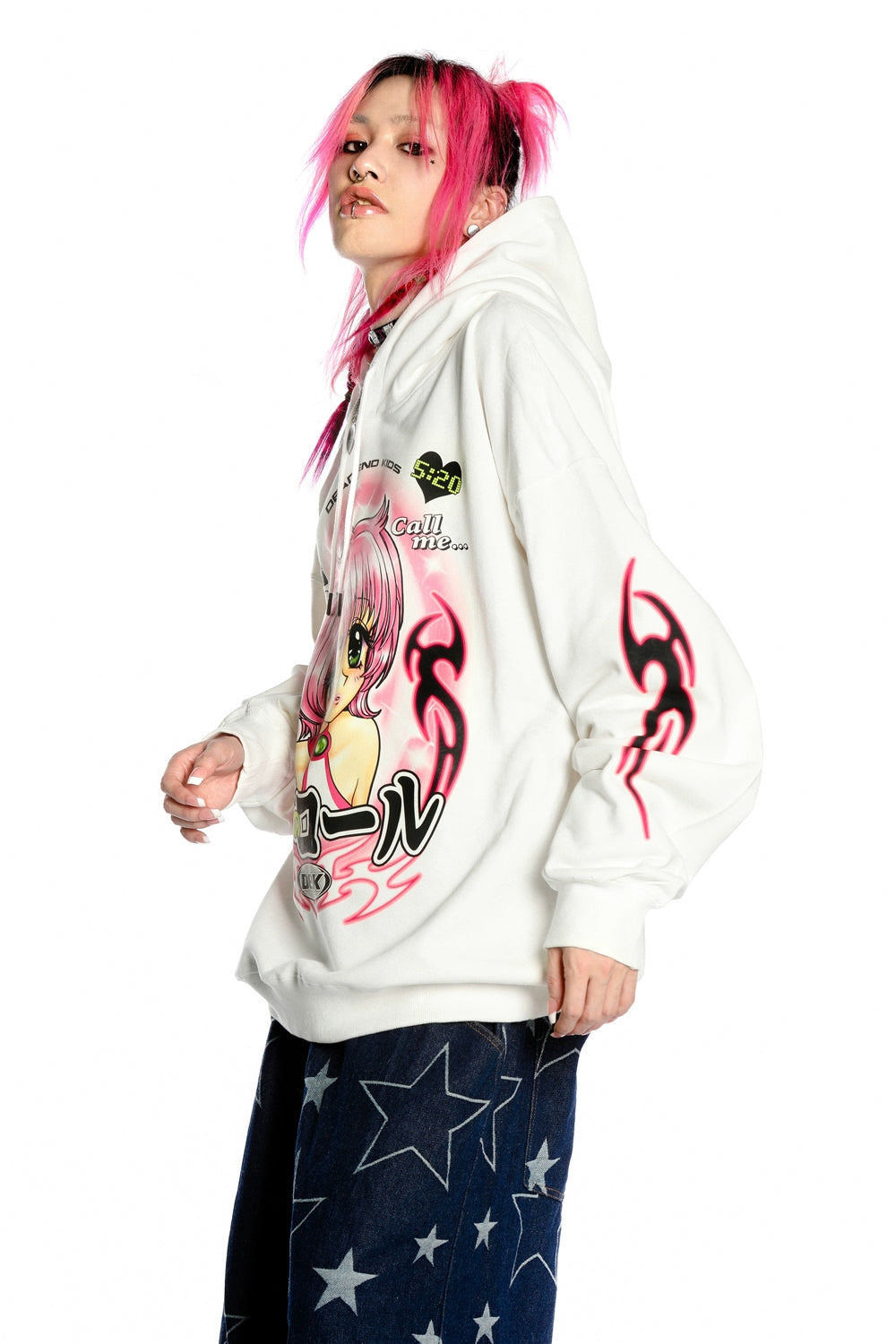 A person with pink hair is wearing the Seakoff Y2K Aesthetic Anime Hoodie featuring retro manga girl graphics and kawaii phone design. They pair it with dark jeans adorned with star patterns, set against a plain white background.