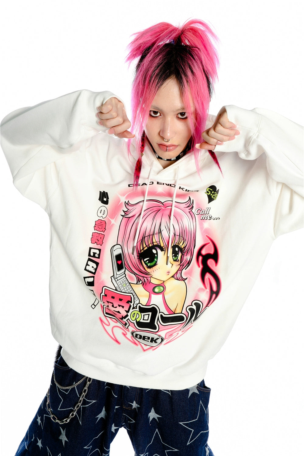 Against a white backdrop, a person with pink hair and facial piercings casually holds the strings of a Seakoff Y2K Aesthetic Anime Hoodie featuring an anime-style pink-haired girl holding a phone.