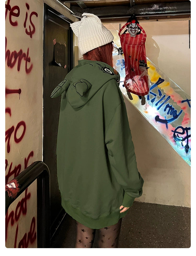 A person with long hair, wearing a white beanie and a Seakoff Springtrap-Inspired Hoodie—400GSM Oversized Green Zip-Up from the Five Nights at Freddy&