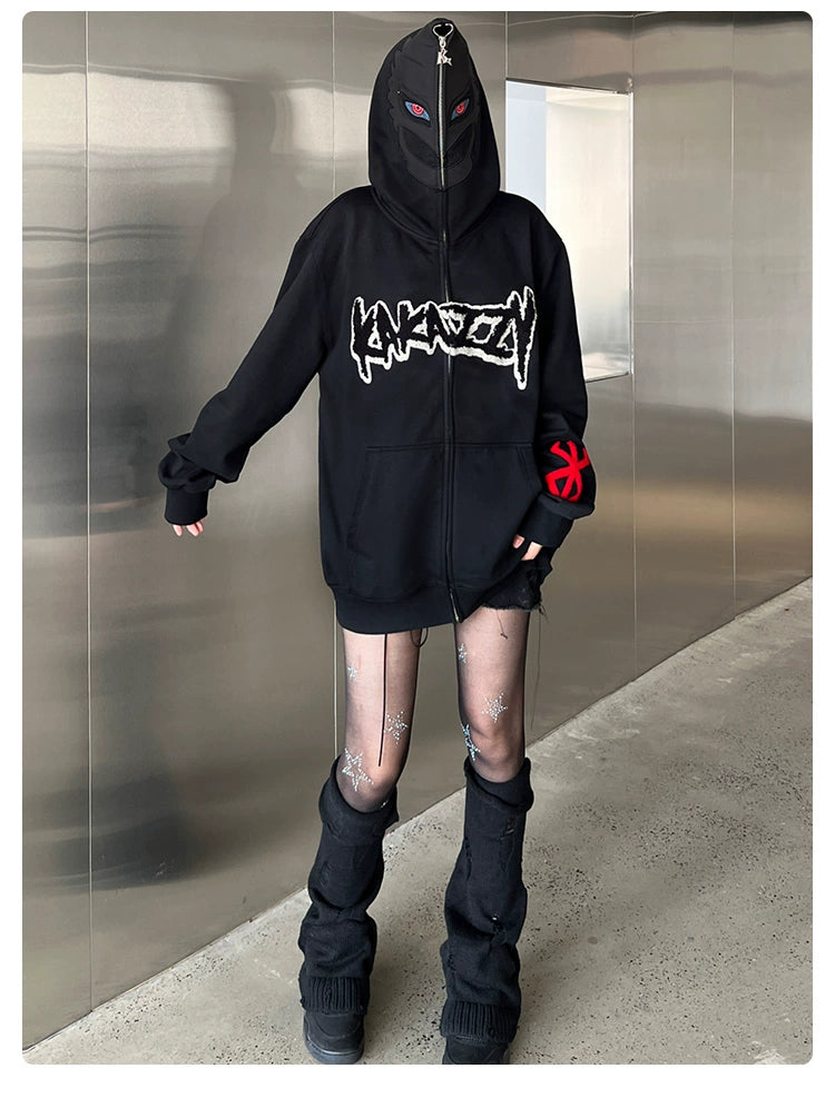 Wearing a Berserk-Inspired Griffith Dark Knight Hoodie, black zip-up oversized streetwear by Berserk, a person stands indoors against a metallic wall. They pair the hoodie with a black mask featuring red eyes, sheer tights, and black leg warmers.