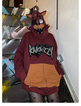 A person stands on stairs wearing a Seakoff Foxy-Inspired Hoodie, an oversized red zip-up sweatshirt with cartoon animal face and ears from Five Nights at Freddy&