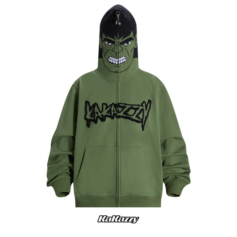 The Seakoff Hulk-Inspired Hoodie is a 400GSM oversized green zip-up sweatshirt with front zipper, two pockets, and a hood featuring an animated face. It sports a black stylized "Kakazzy" logo, perfect for superhero fans and streetwear enthusiasts who love bold style.
