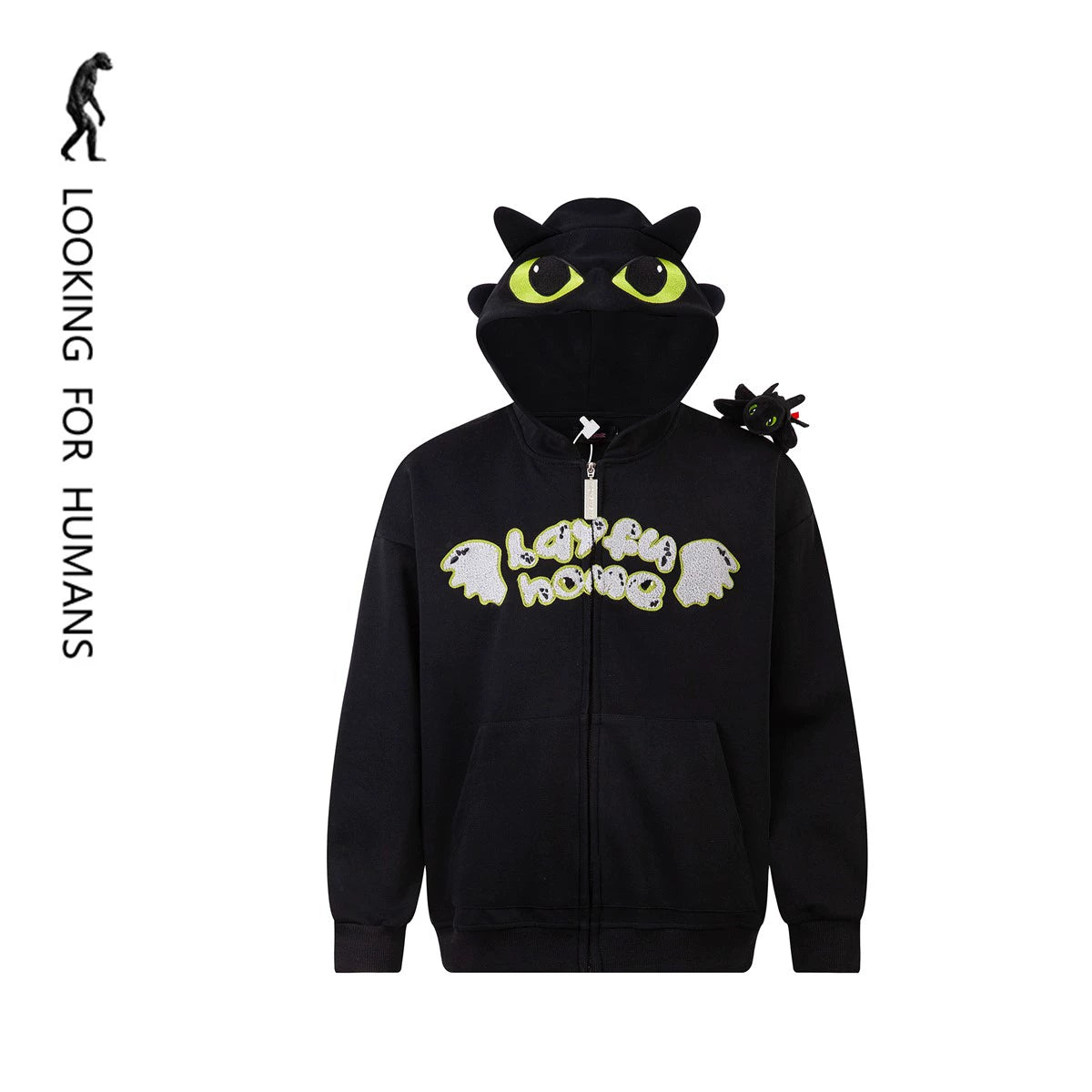 The Seakoff Cute Night Fury Dragon Hoodie is a black anime-inspired full zip hoodie featuring large green eyes and 3D ears on the hood, with "Looking for Humans" on the chest. Ideal for fans, it includes a small plush toy resembling Night Fury from How to Train Your Dragon on the shoulder.