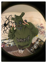 Dressed in a Seakoff Springtrap-Inspired Hoodie, an oversized 400GSM green zip-up sweatshirt with a cartoonish face, the person indoors flashes peace signs. The room, ideal for Five Nights at Freddy&