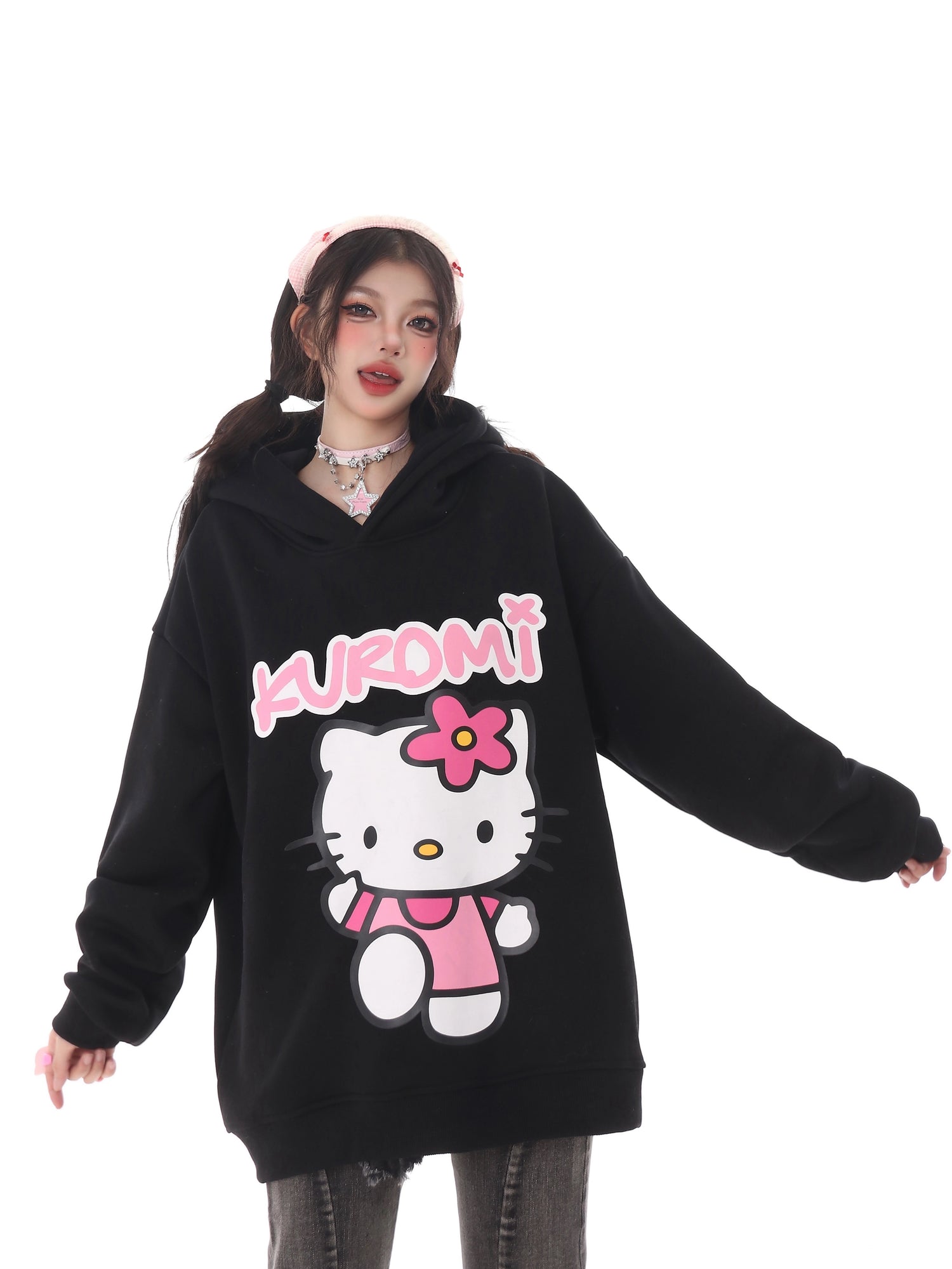 A person in a Seakoff Kawaii Hello Kitty Oversized Hoodie with Kuromi from Sanrio sports a kawaii look. They have long dark pigtails, a pink headband, choker, and gray jeans—ideal for true Sanrio fans.