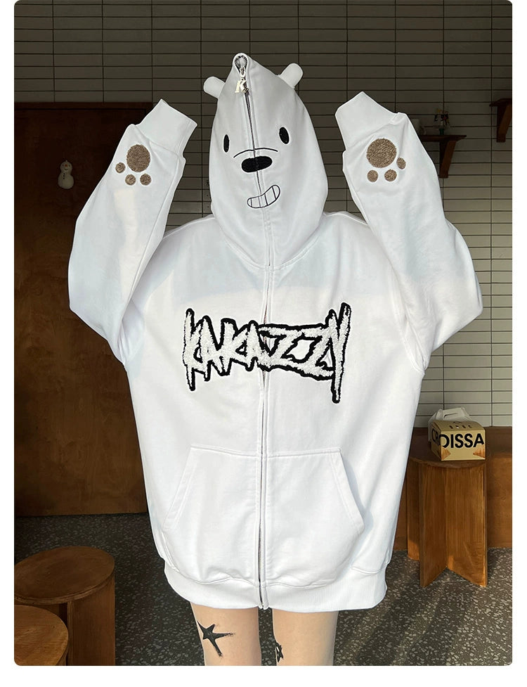 Someone is wearing a Seakoff Cute White Bear Hoodie, featuring an oversized fit with bear ears and a charming polar bear design hood. The word "ANXIETY" is embroidered on the front in black. A wood-paneled wall and small box add to the cozy vibe of the setting.