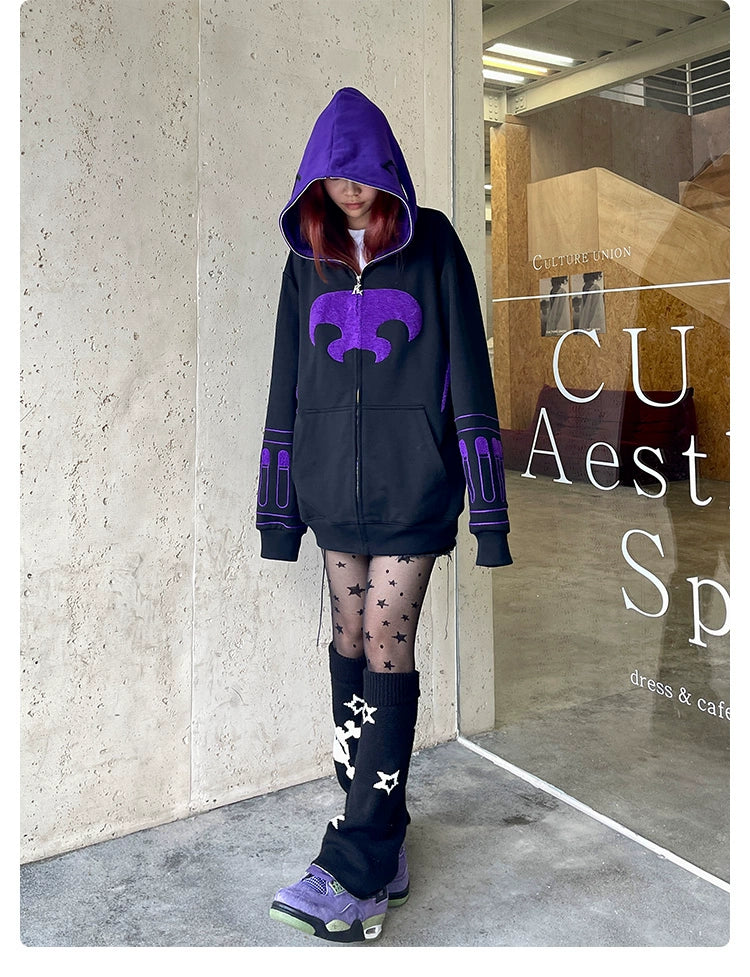 A person wearing the Seakoff Dark Hero Hoodie, an oversized black and purple superhero zip-up sweatshirt, poses against a wall. Paired with star-patterned tights and matching leg warmers, they evoke a dark hero vibe by a glass door with white text, capturing superhero fans&