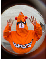 Wearing a Seakoff Furious Orange Bear Hoodie with red embroidery and an Angry Bear design, a person holds their hands up. The hoodie, made from premium 400GSM cotton, is captured in a fisheye effect.