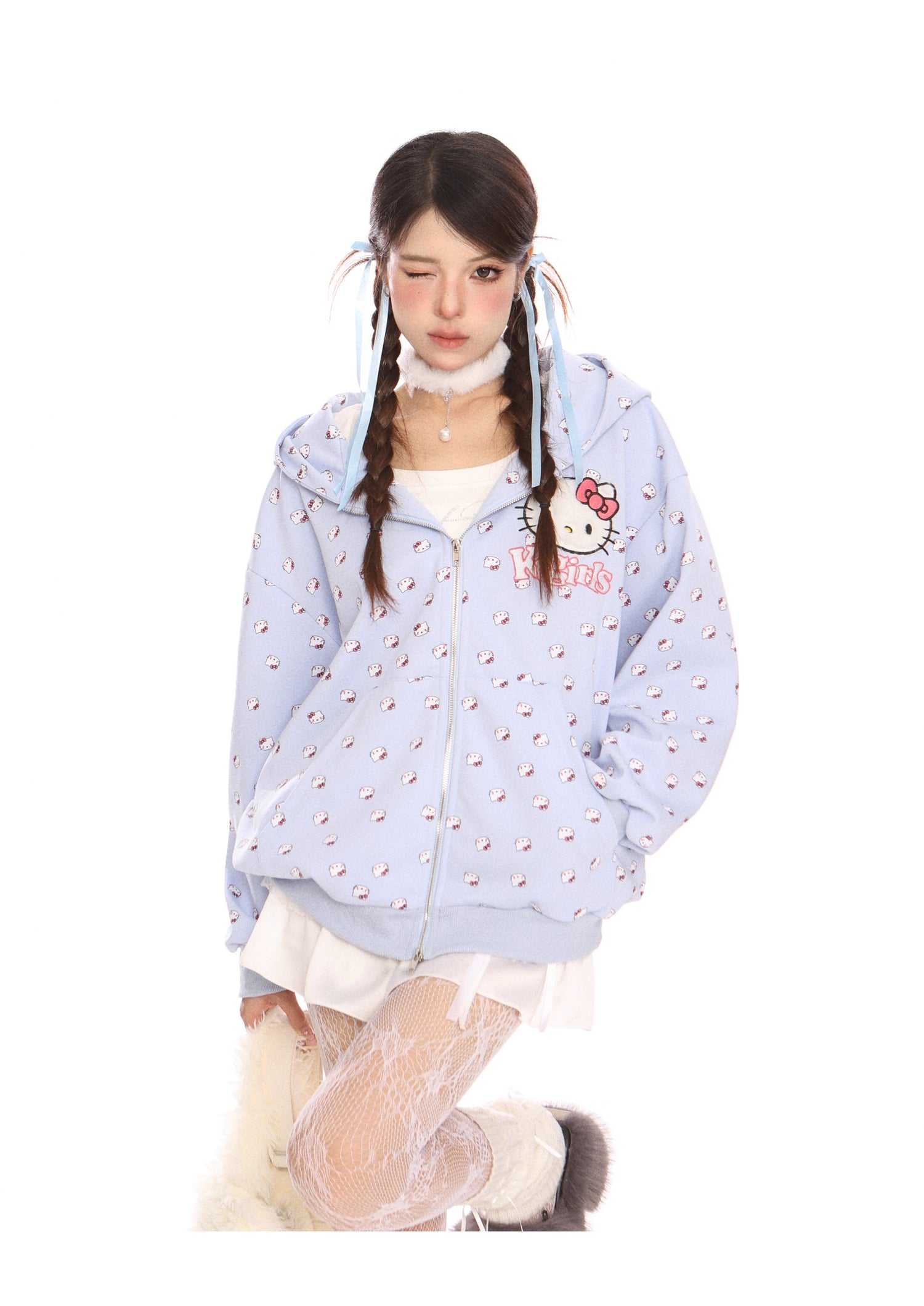 A person with long braided hair is wearing a Hello Kitty Pink Kawaii Hoodie from Seakoff, featuring a cute oversized zip-up with cat ear hood and all-over print. They pair it with a white dress and patterned tights, winking and tilting their head slightly to embrace the kawaii style.