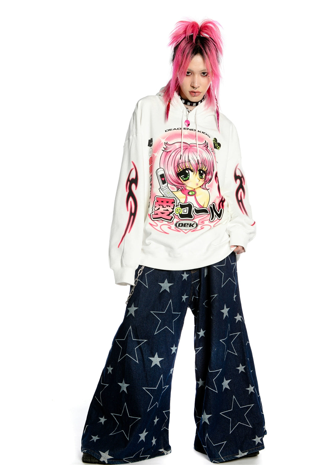 A person with pink hair is wearing Seakoff’s Y2K Aesthetic Anime Hoodie featuring a retro manga girl and kawaii phone design, along with star-patterned wide-leg pants, exuding the Y2K vibe against a plain white background.