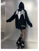 A person stands with their back to the camera, wearing a Seakoff Venom Spider Hoodie. Their sheer star-patterned tights and black boots with star designs complement the look, capturing streetwear vibes within a metallic-looking room.