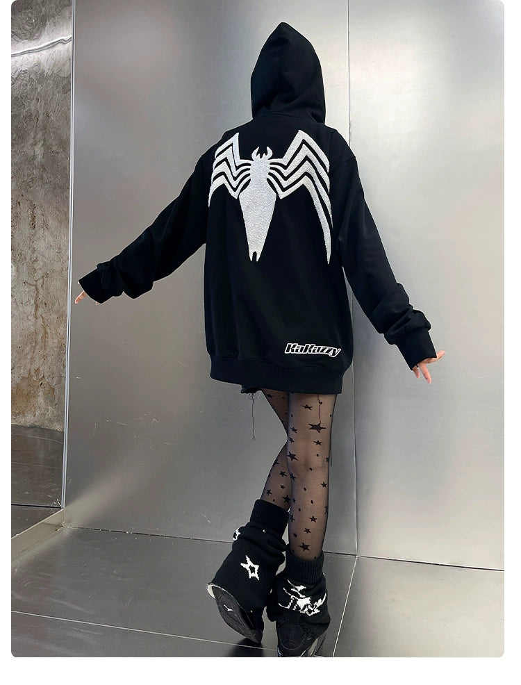 A person stands with their back to the camera, wearing a Seakoff Venom Spider Hoodie. Their sheer star-patterned tights and black boots with star designs complement the look, capturing streetwear vibes within a metallic-looking room.