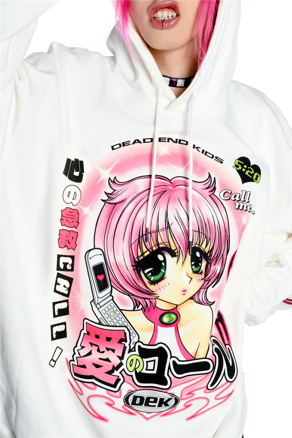 A person with pink hair wears the Seakoff Y2K Aesthetic Anime Hoodie, featuring a pink-haired anime character with green eyes and a kawaii phone. The design includes Japanese and English text, along with "DEAD END KIDS" in a retro manga style.