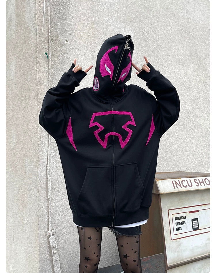 A person in a Seakoff "Futuristic Warrior Hoodie" with sci-fi pink and black designs obscures their face under the hood, standing against a light-colored wall. Star-patterned tights enhance their style as they make a horn gesture. The "INCU SHOP" sign is partially visible behind them.