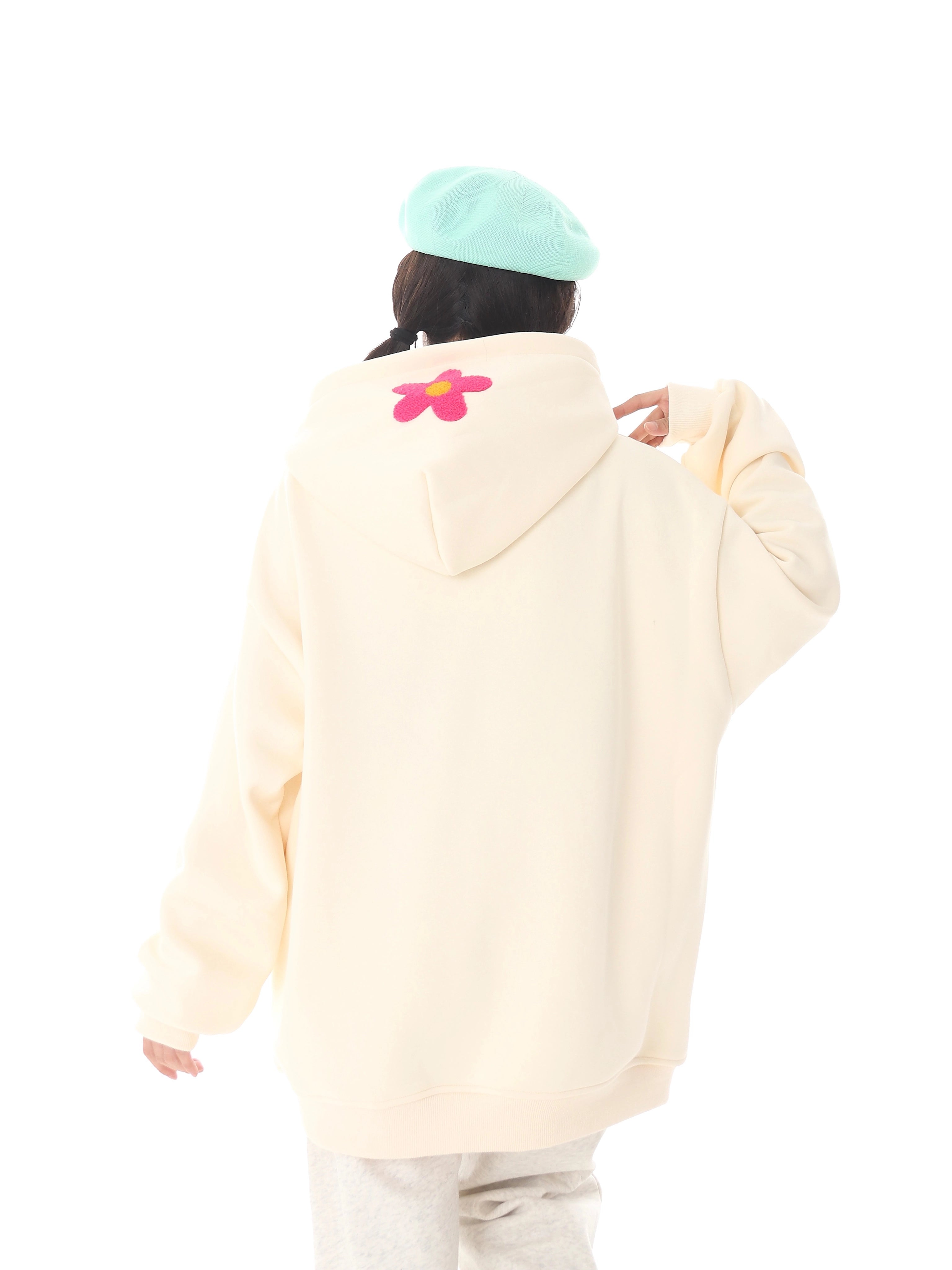 A person sports a Seakoff Kawaii Hello Kitty Oversized Hoodie, a cute pastel anime pullover perfect for Sanrio fans. Paired with a light blue hat and set against a white backdrop, their style highlights playful flair.