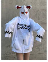 A person is wearing an oversized Seakoff Fierce Bunny Hoodie in 400GSM cotton, featuring a large cartoon face and long sleeves. The hood has playful bunny ears with bold "Kaka" print. A plain concrete wall backdrop highlights the unique style of the hoodie with red eyes.