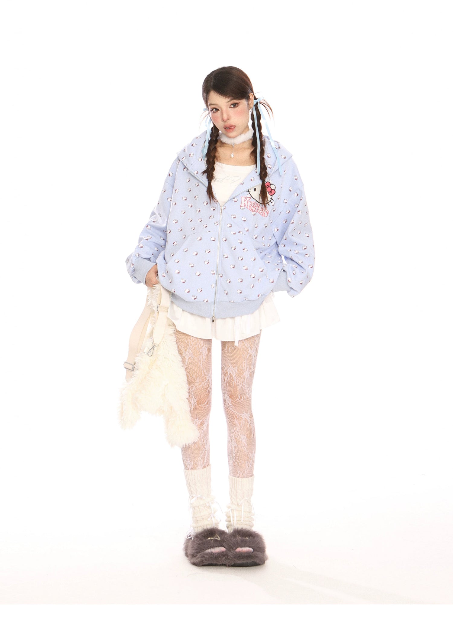A person embraces kawaii fashion against a plain white background, wearing a Seakoff Hello Kitty Pink Kawaii Hoodie with cat ear hood, white textured leggings, and fluffy slippers. They hold a fluffy white bag and sport pigtails.