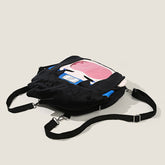 A black Seakoff backpack with adjustable straps lies on a plain background, embodying anime collectibles. It features a colorful cartoon face with pink, blue, and white elements, similar to the Naruto Sasuke Uchiha Plush Shoulder Bag&