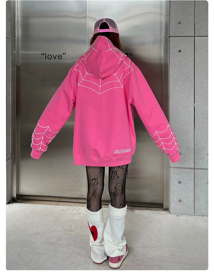 A person wears a Seakoff Spider-Inspired Hoodie - a 400GSM oversized pink zip-up superhero sweatshirt, paired with black fishnet stockings, white leg warmers, and a pink cap, standing back to the camera as "love" gleams on the metallic background. Perfect for stylish superhero fans!.
