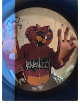 A person in a Seakoff Foxy-Inspired Hoodie, featuring a cartoon animal face on the hood, has their hands raised. Distorted by a fisheye lens effect, the scene echoes Five Nights at Freddy&