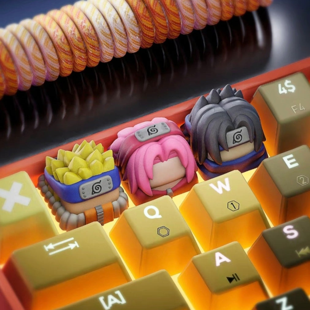 A close-up image of a mechanical keyboard with custom keycaps designed to resemble stylized characters with distinct headbands. The keyboard keys are orange and yellow, and a coiled cable is placed above.