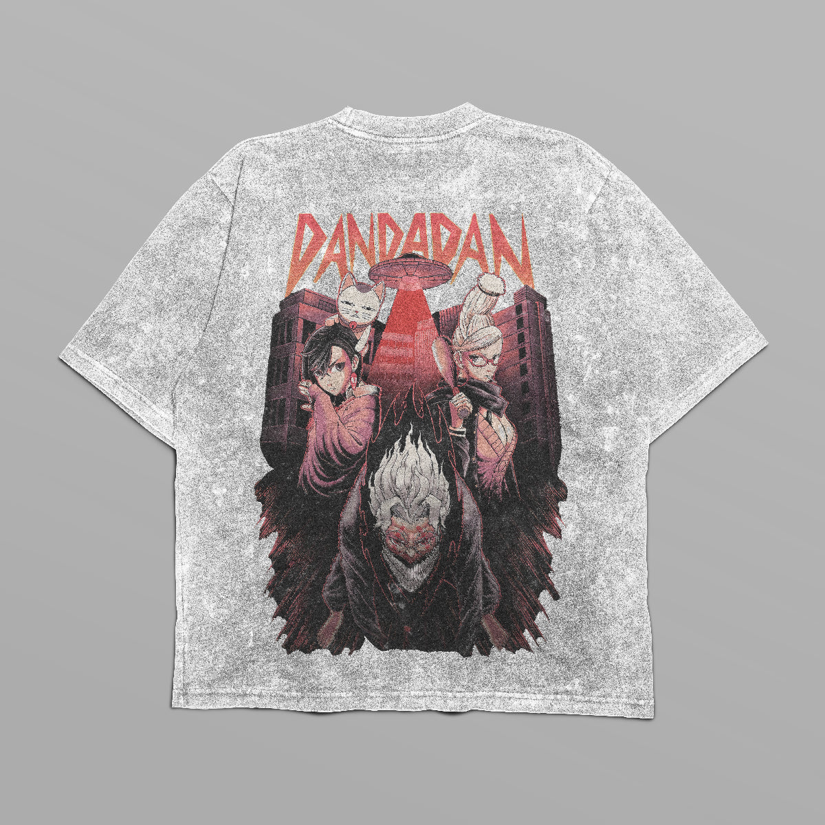 The Dandadan Oversized T-Shirt features a front logo and a back design with three anime characters under the stylized "DANDADAN" text. The urban backdrop has a reddish tint. Part of our streetwear line, it&