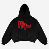 The Dandadan Hoodie by Dandadan features a manga-inspired design with bold red lettering on black, crafted in premium 360 GSM cotton. It has a front pocket and ribbed cuffs, and lies flat on a light gray background, capturing the Okarun manga panel aesthetic.