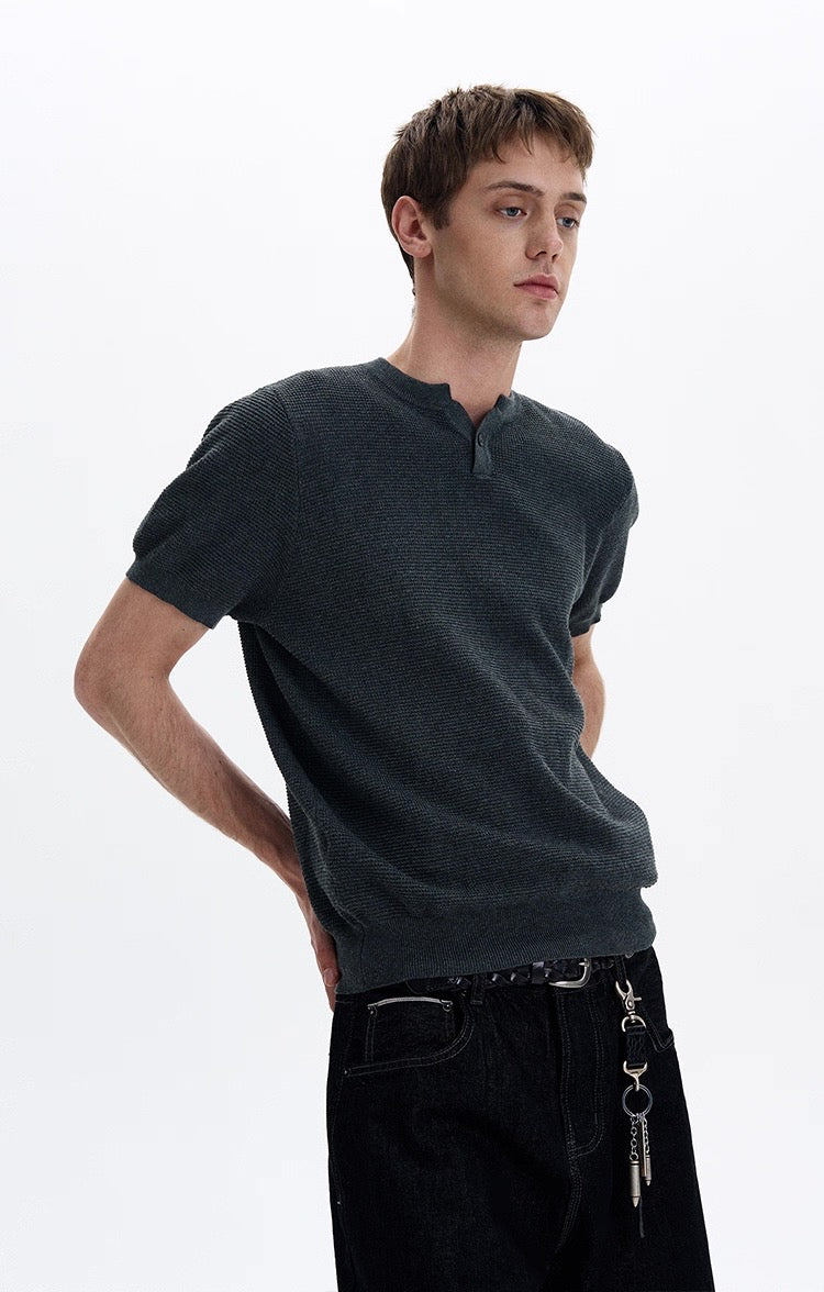 Dark textured knit short sleeve polo tee worn by a model with black jeans and a chain belt