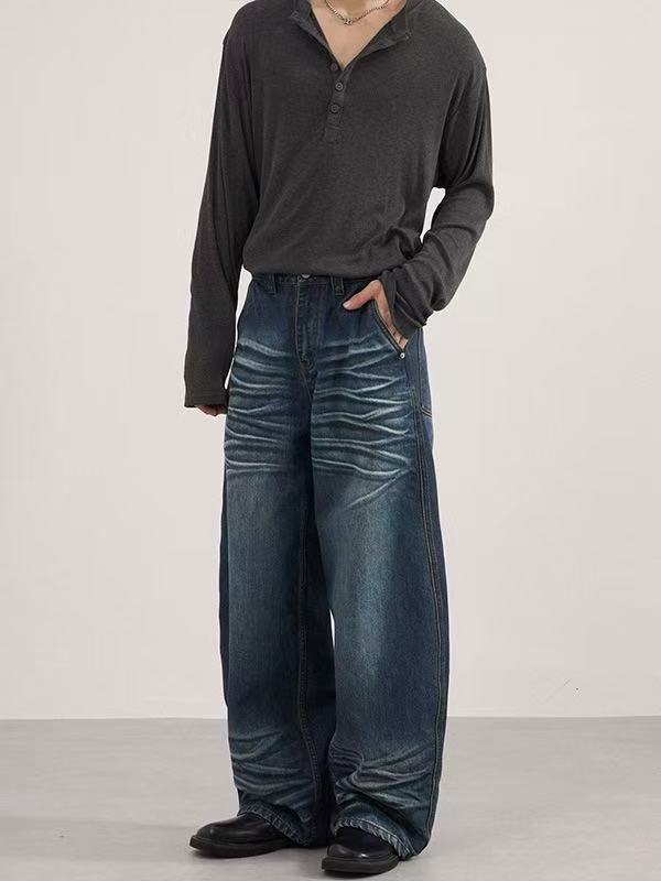 Model wearing dark blue baggy jeans with stacked whisker fading on the front