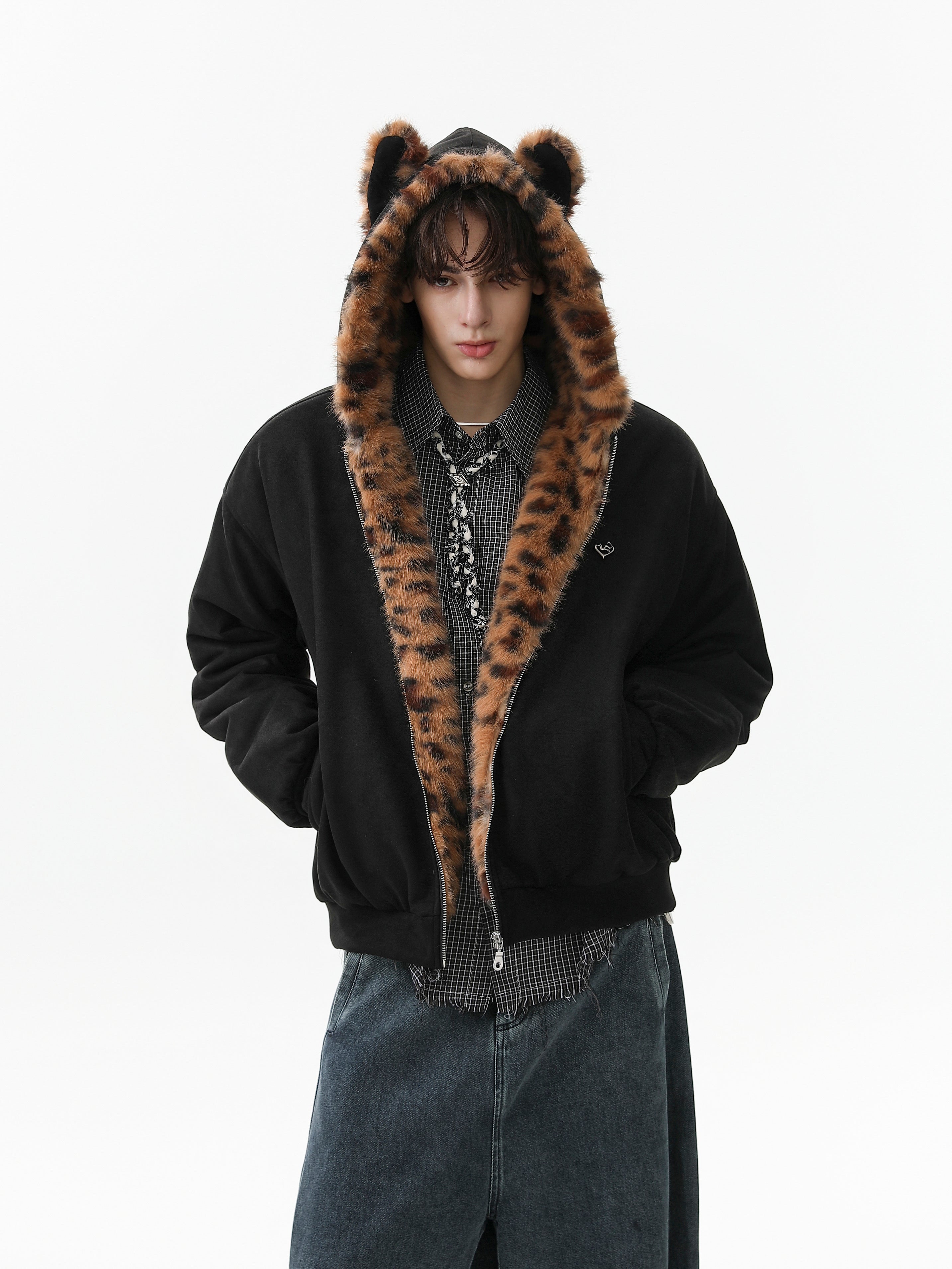 Man wearing a black bomber jacket with leopard faux fur hood trim and bear ears, styled over a plaid shirt and wide-leg jeans