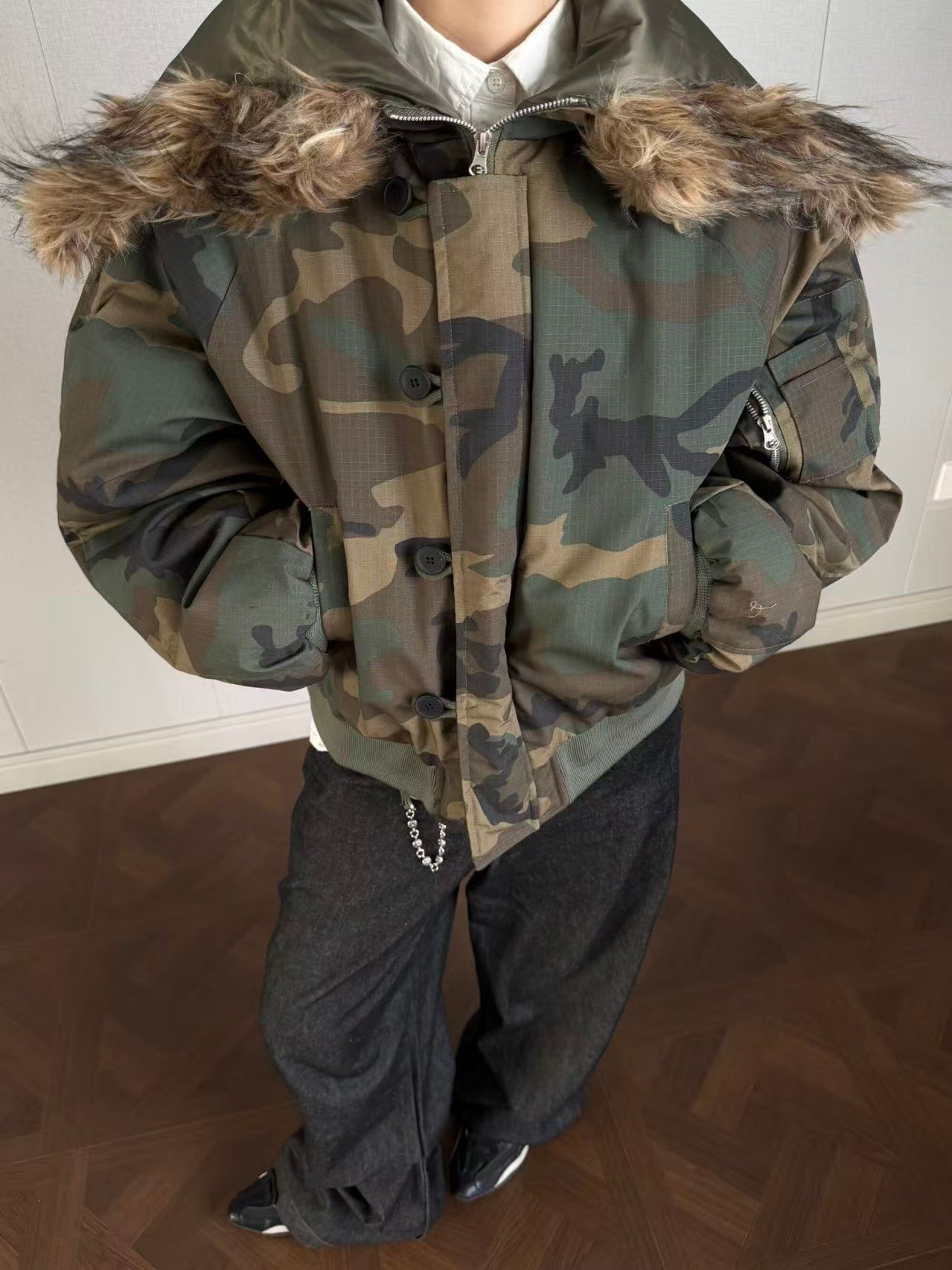 Model wearing dark camouflage cropped bomber jacket with faux fur hood, front view