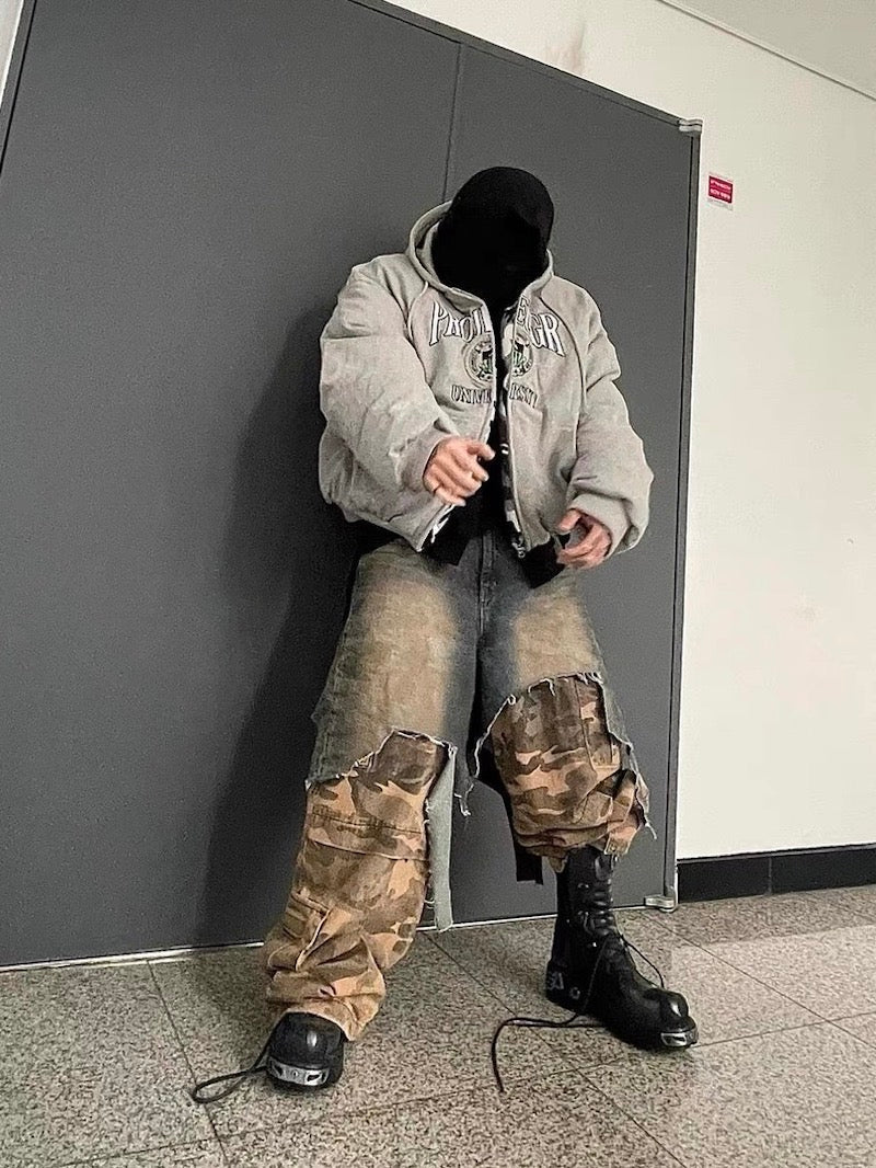 Model wearing layered denim and camouflage cargo pants in a front view indoors