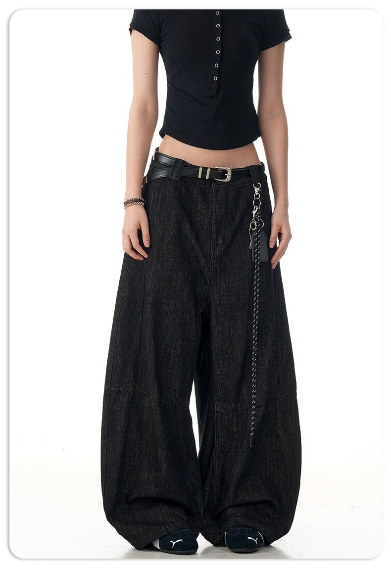 Front view of black barrel leg denim pants worn on a model with a belt and chain accent