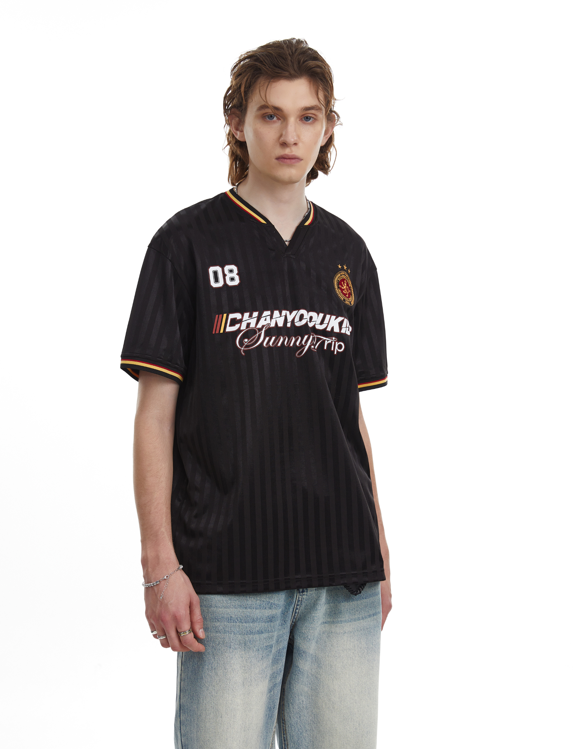 Black varsity-style mesh soccer jersey tee with striped trim, chest graphics, and relaxed fit on model
