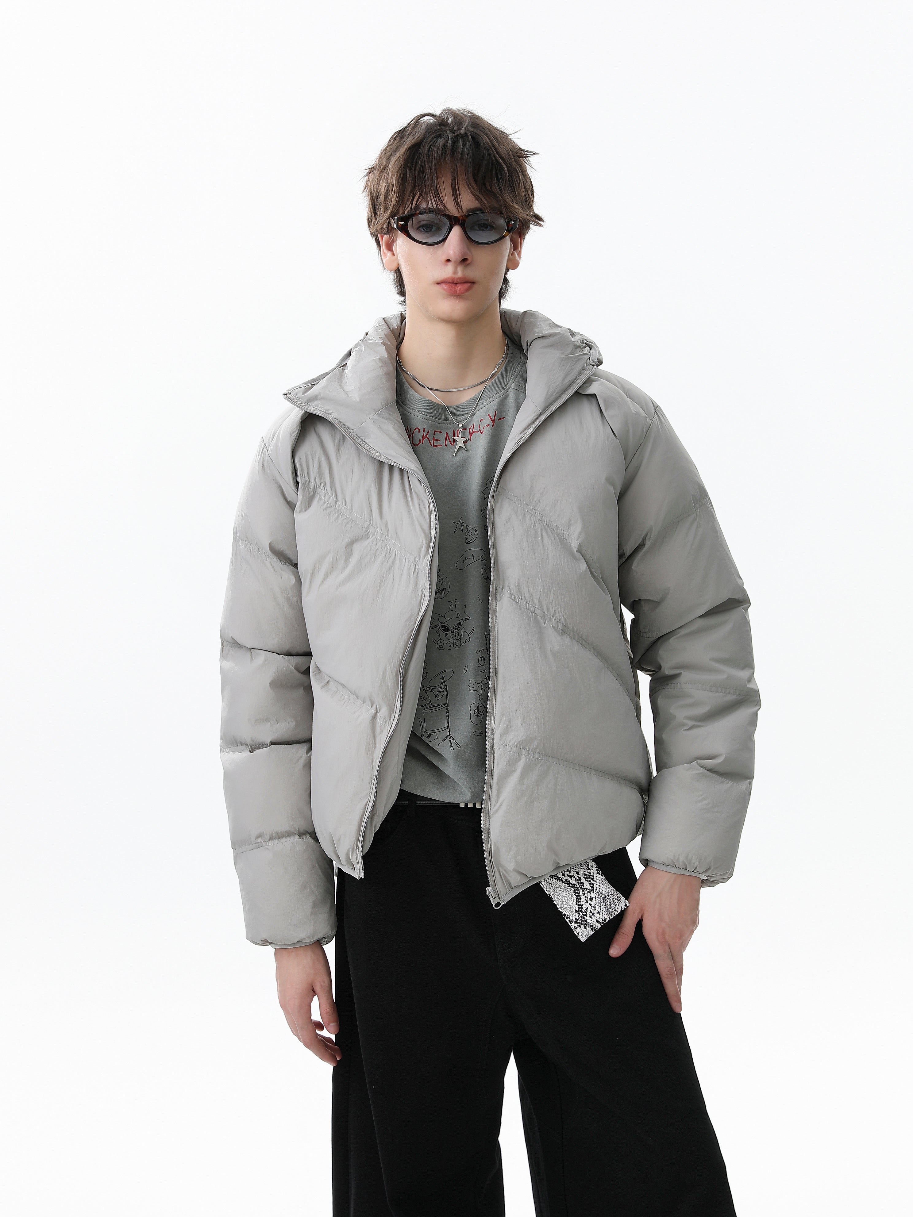 Model wearing light gray hooded puffer jacket with diagonal zipper, front view