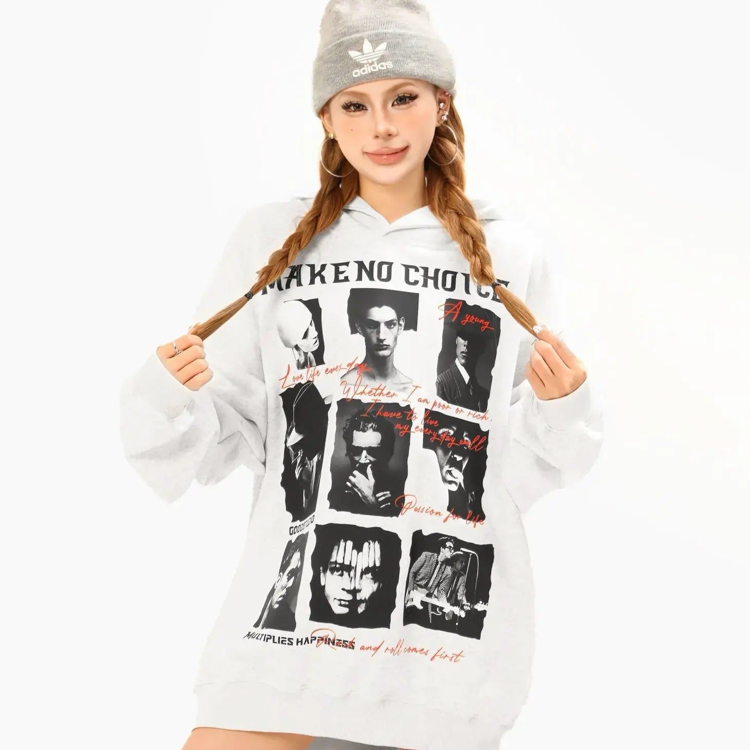 A woman wearing a gray Adidas beanie and a white oversized hoodie dress with MAKE NO CHOICE and various black-and-white images of movie characters, along with red handwritten text, poses while holding the sides of her hoodie.