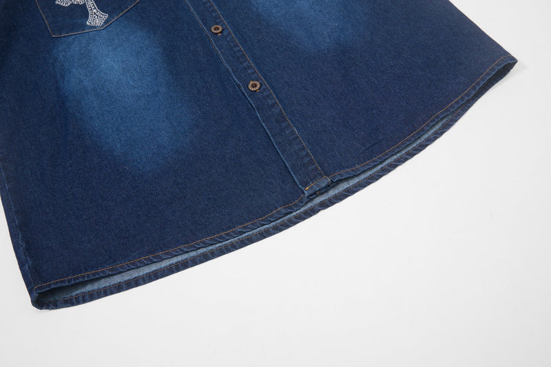 Dark blue denim button-up shirt with rhinestone cross detail and stitched hem, shown laid flat on a white background