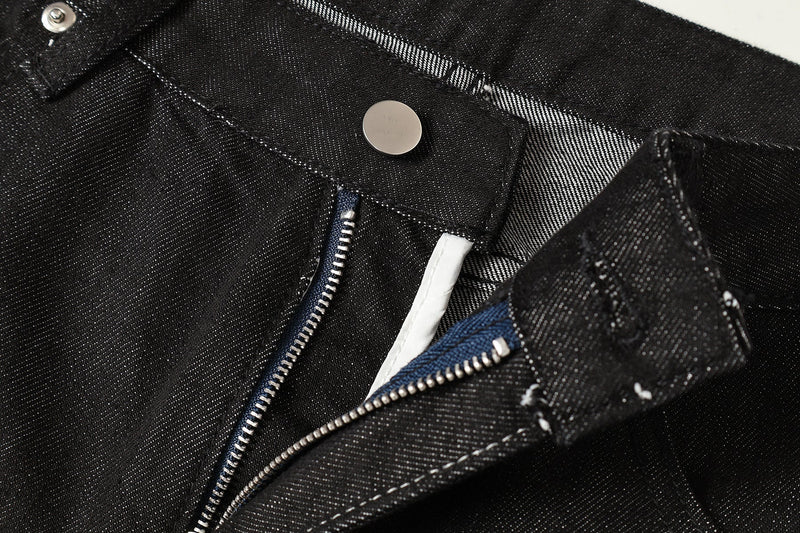 Close-up of front fly with silver snap button and zipper on black denim