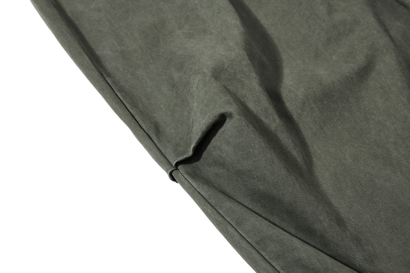 Close-up of olive green pant leg with wide drape and folded hem