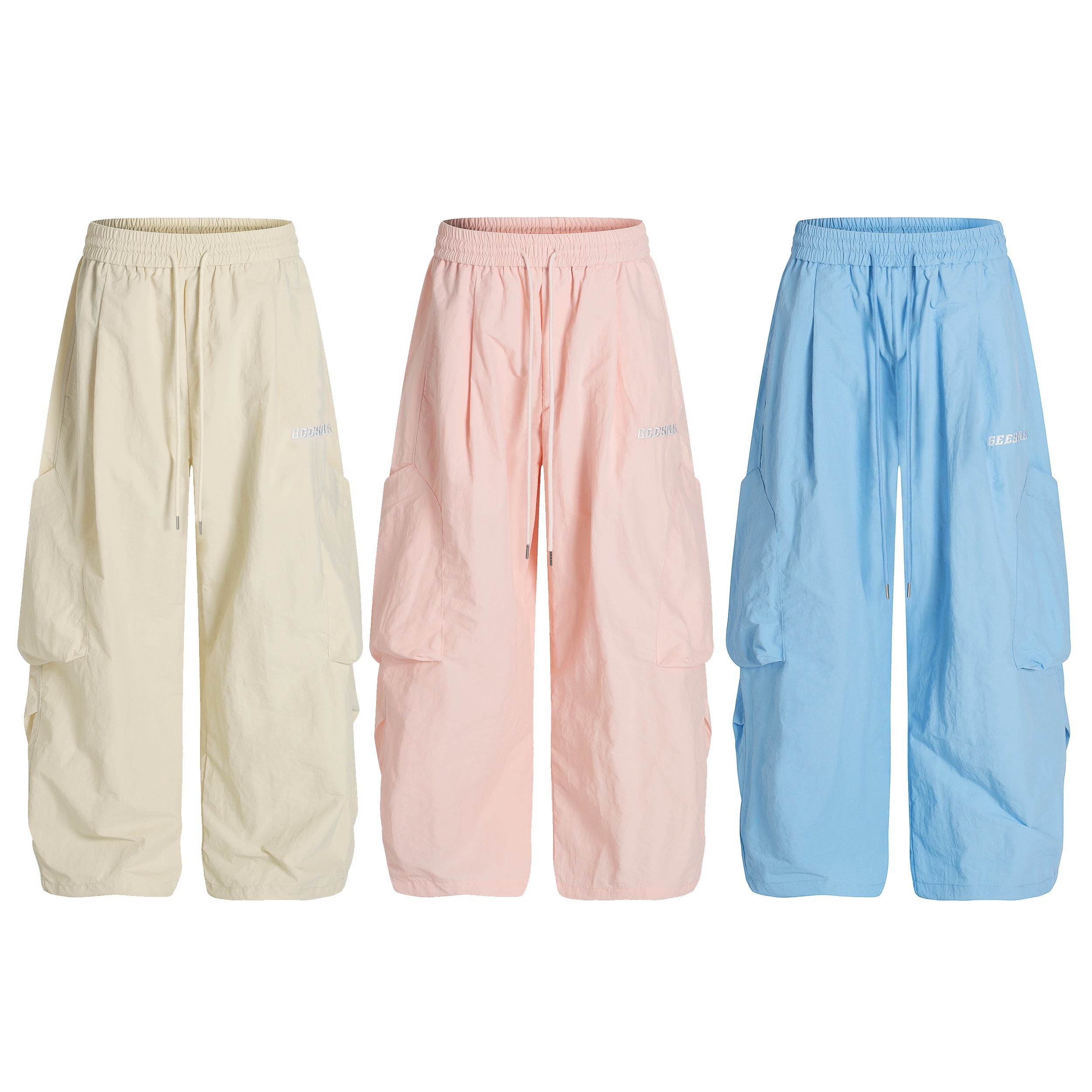 Three pairs of wide-leg nylon cargo pants in cream, pink, and blue displayed side by side on a white background