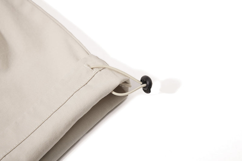 Close-up of beige pant cuff with adjustable drawcord stopper