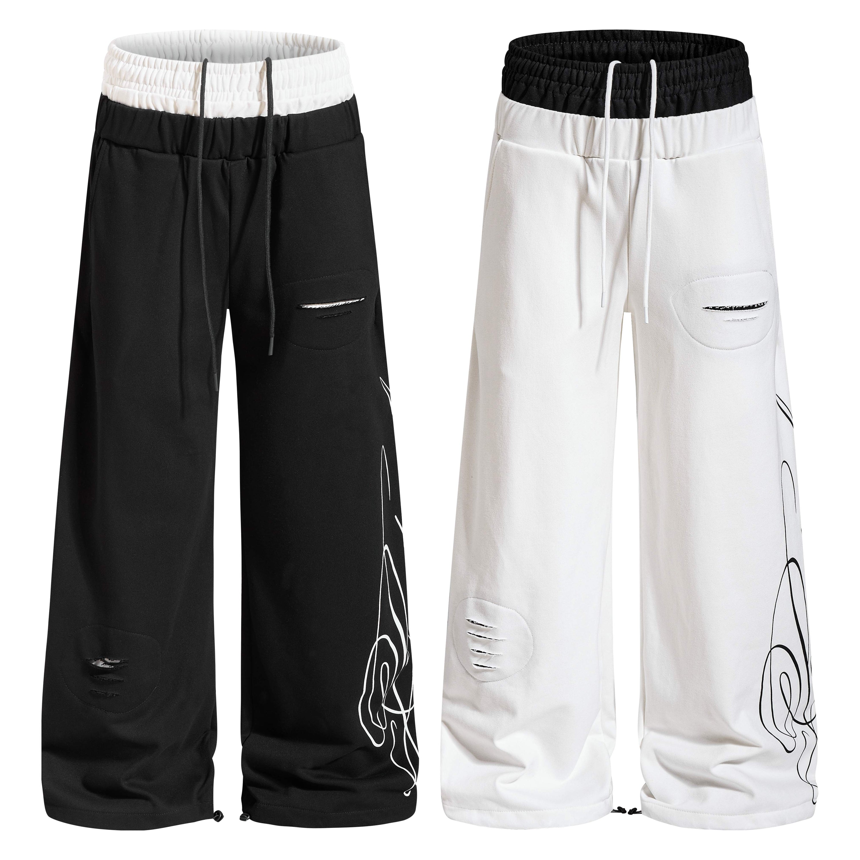 Black wide-leg sweatpants with white contrast waistband, distressed rip detailing, and abstract graphic print on the leg