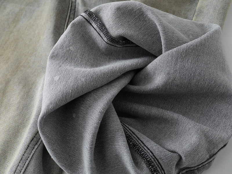 Close-up of folded grey wash denim fabric showing the thick seam and textured twill